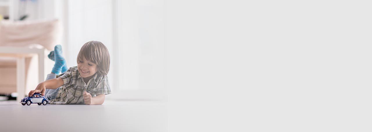 Αγόρι που παίζει με ένα αυτοκινητάκι στο πάτωμα.