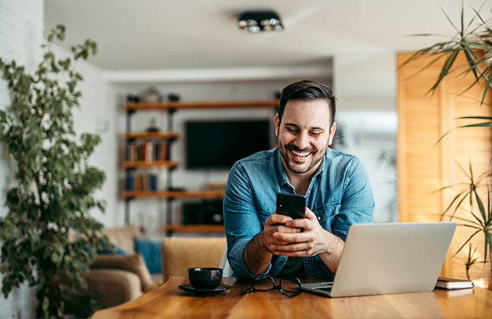 Ένας άντρας κοιτάζει το κινητό του στο σπίτι του